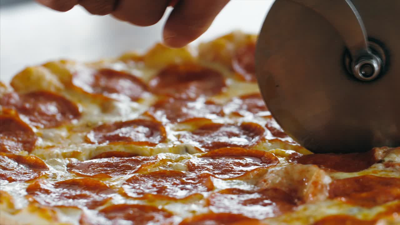 롤러 피자 커터 를 사용 하여 살라미 피자를 조각 으로 잘라내는 여자 의 손