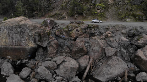 Drone-flying-over-lake-toward-parked-car-waiting-for-adventure