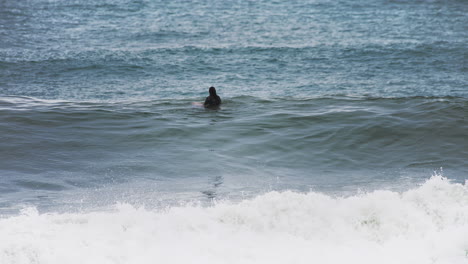 surfer sitting in the board waiting for a wave in the shore on tough weather condition day