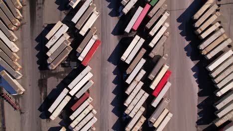 Sideways-aerial-view-of-many-container-dock-at-Vancouver-shipping-terminal-beside-railway,-Canada