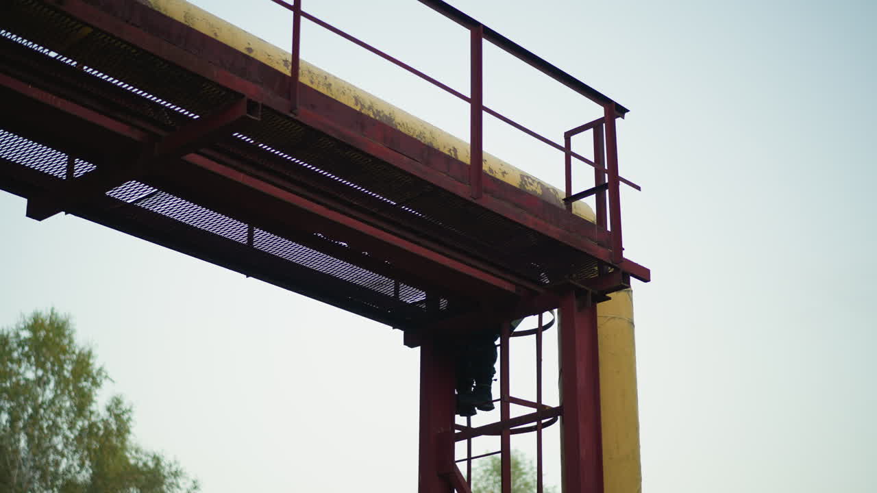 rusted metal catwalk with climber, ascending vertical ladder beneath pale sky, weathered girders and railings, distant tree line, industrial maintenance vibe, adventurous tension, textured corrosion