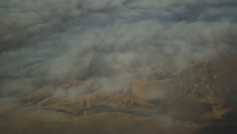 flying high above the namib desert, with early morning fog over the dunes