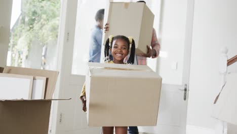 happy african american couple with son and daughter bringing boxes into house, slow motion