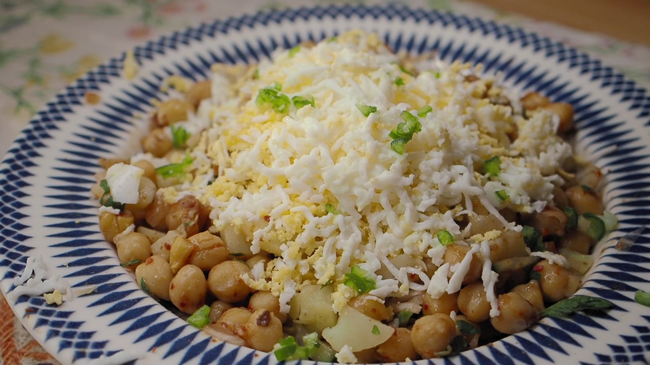Garnishing Healthy Chickpea Salad with Grated Egg and Green Onions