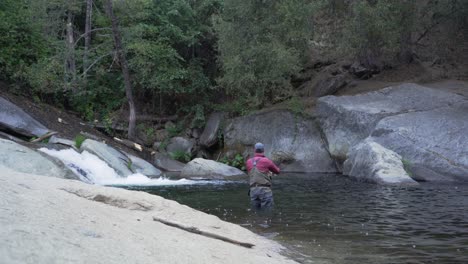 tiro estático, hombre pescando con mosca en el río de montaña por cascada, fundición