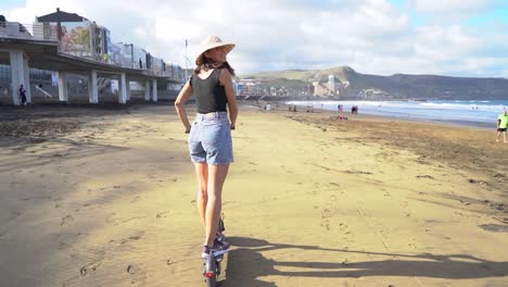 linda mujer montando scooter eléctrico en la playa de gran canaria a orillas del mar siguiendo la línea de la costa