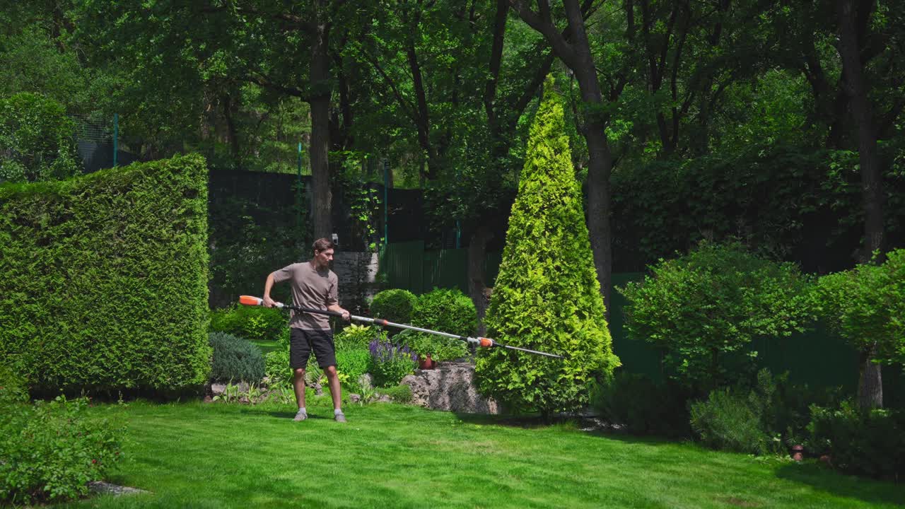 Man Trimming Evergreen Bush in a Green Garden