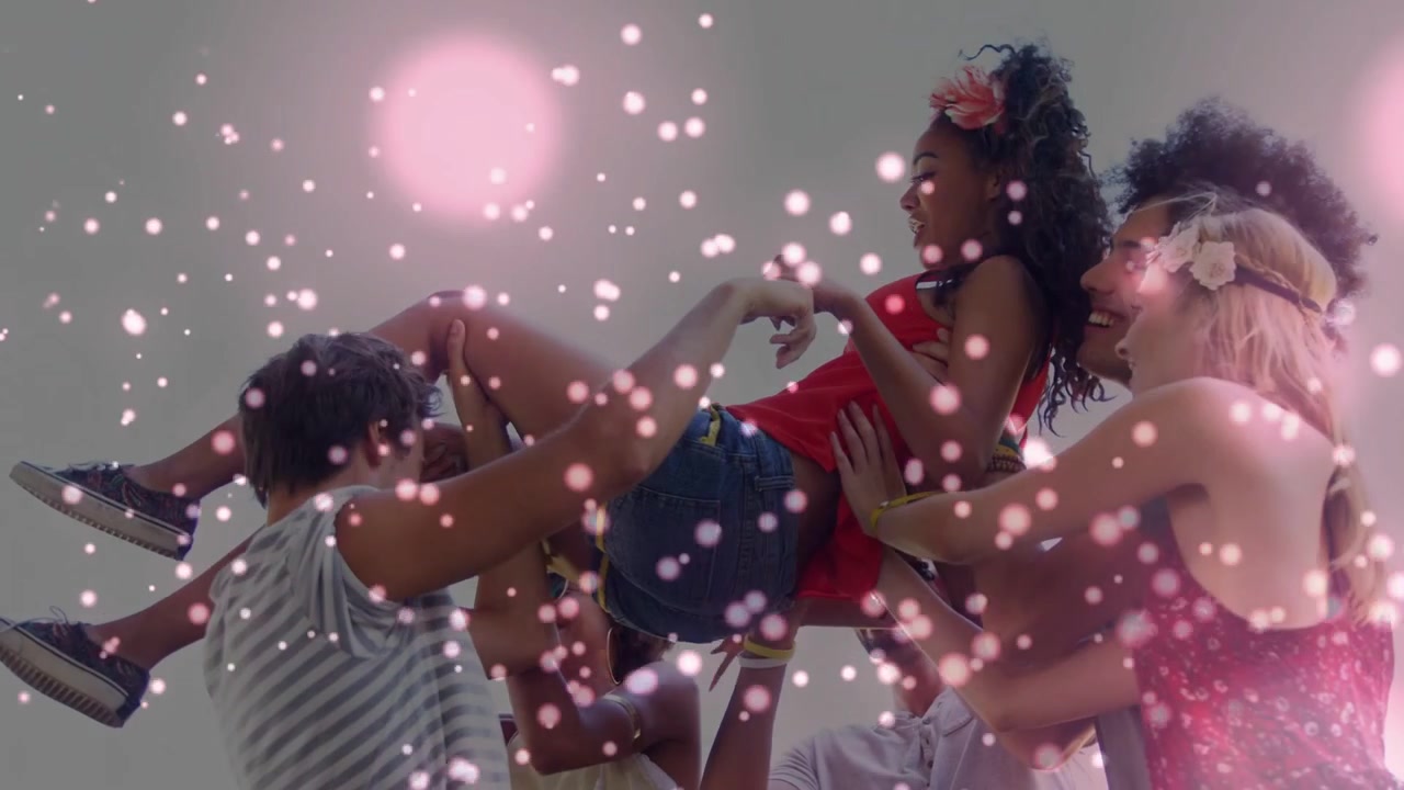 Friends initiating cheer and lifting woman in studio showcasing fashion with animated pink confetti