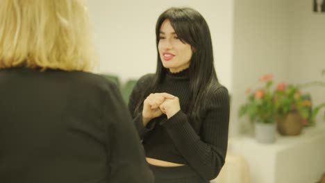 검은색 의상을 입은 전문적인 여성 관리자가 사무실을 걸어다니며 동료들과 상호 작용하며 문서와 노트북을 들고 리더십과 전문성을 보여주고 있습니다.
