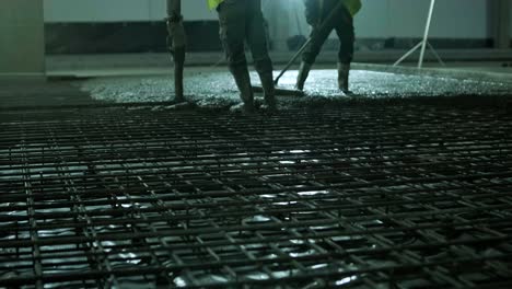 reinforced concrete. worker concretes foundation, rebar, pour cement mortar on reinforcing mesh. builders are building a factory, hangar.