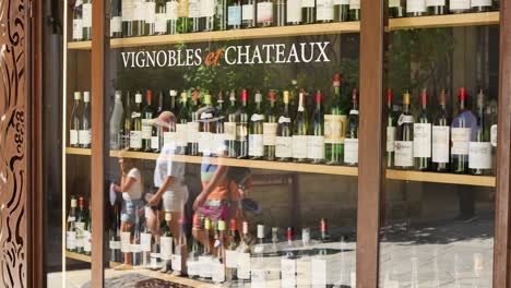 people browsing wine bottles in a shop window