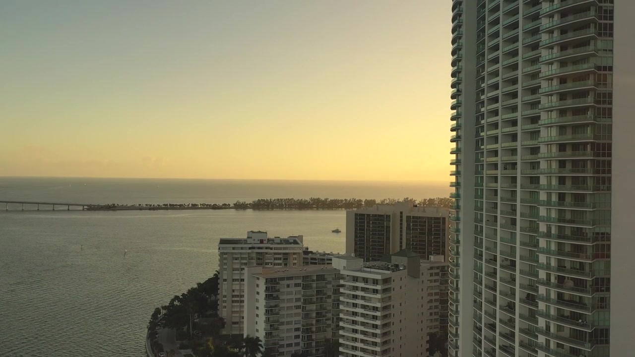 Tomada aérea cinematográfica de um edifício icônico em Brickell Drive, em Miami, Flórida, ao pôr do sol durante a hora dourada.