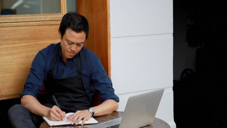 waiter using laptop and writing on notepad 4k