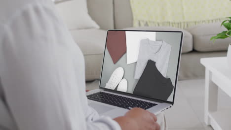 mujer biracial usando una computadora portátil en casa para comprar en línea, cámara lenta
