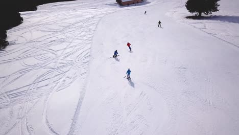 people skiing and snowboarding on snow slope in winter ski resort