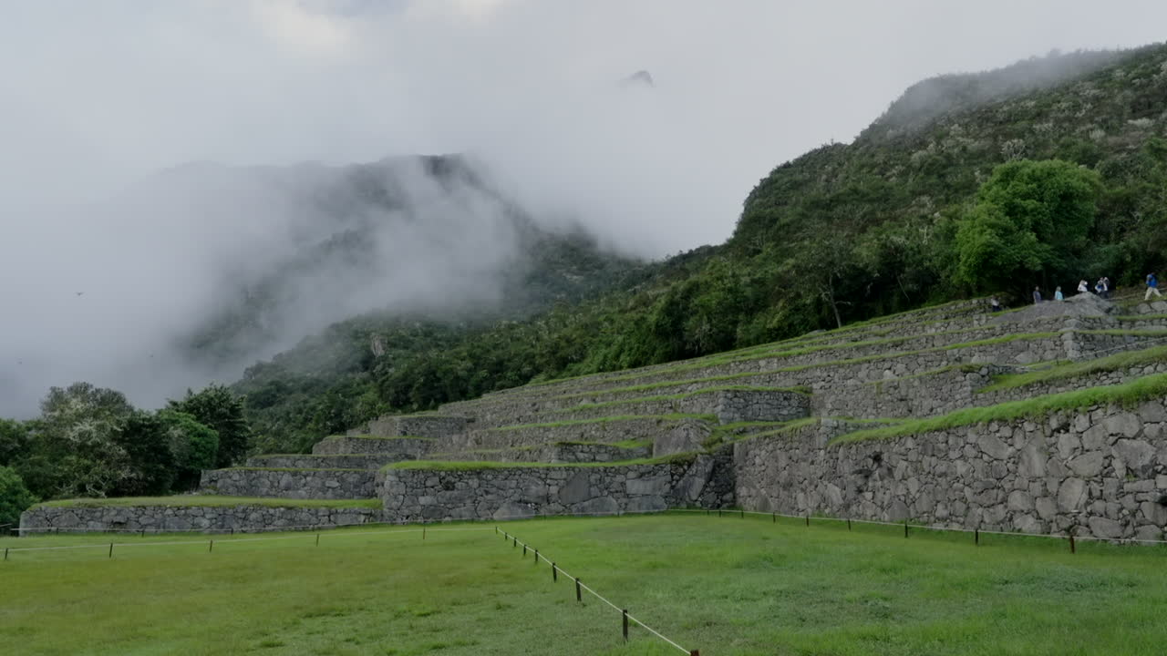 Tourists walk over Machu Picchu stone terraces. Inca ancient lost city ruins in Cusco, Peru. Wide landscape