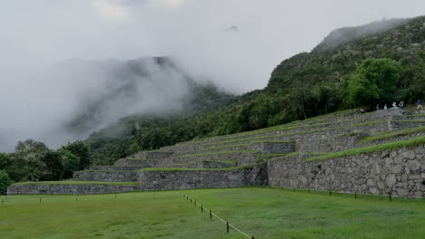 tourists walk over machu picchu stone terraces. inca ancient lost city ruins in cusco, peru. wide landscape