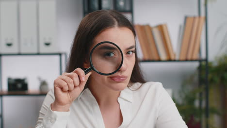 business woman holding magnifying glass near face looking with big zoomed eye searching analysing