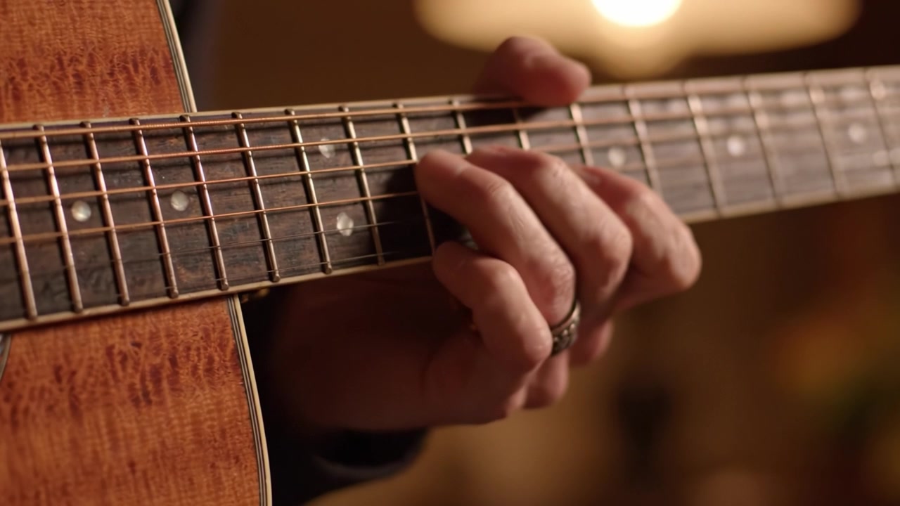 Un primo piano di mani esperte che suonano la chitarra: catturando l'arte e la passione dietro un'esibizione di musica acustica in un ambiente caldo e intimo.