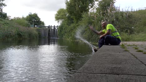 Warehouse-Man-Takes-A-Short-Break,-Splashing-The-Water-From-The-River-Canal-In-Dublin,-Ireland