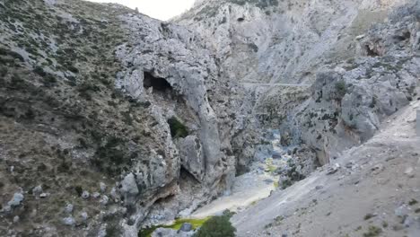 Drone-shot-through-steep-rocky-cliffs-between-wild-mountain-gorge-of-Kourtaliotiko