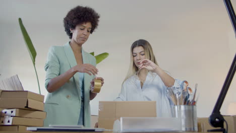 two female entrepreneurs preparing parcel for shipment