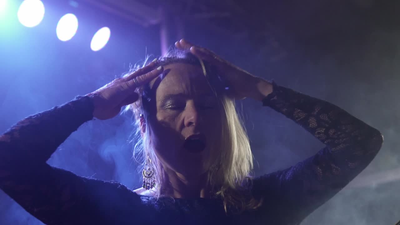 músico femenino tocando el bajo y cantando con acción en el club nocturno