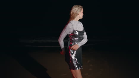 niña de noche divirtiéndose en la playa del océano. enérgica mujer feliz bailando en la orilla del mar