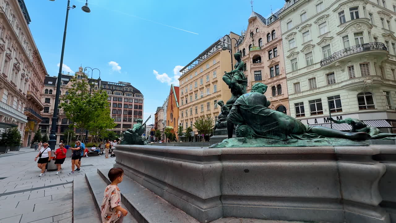 Vienna, Austria - June 9, 2025: Tourists at Vienna's fountain. Tourists stroll near a magnificent fountain surrounded by elegant architecture in central Vienna on a sunny day