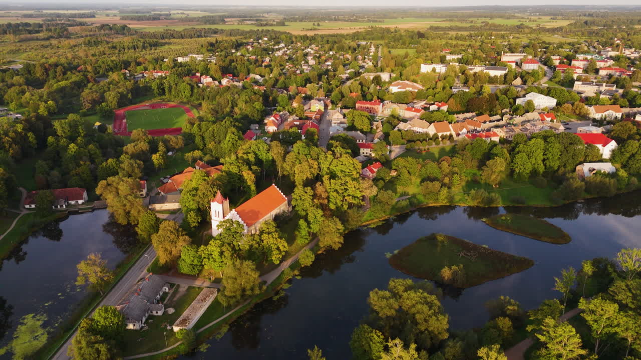 A picturesque aerial establishing of idyllic European town with fall foliage, Aizpute Latvia, its rivers, greenery, and charming rural landscapes centered