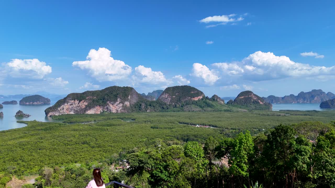 A serene aerial view of Phang Nga Bay, showcasing lush mangroves, limestone cliffs, and a lone photographer capturing the scenic beauty