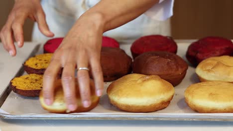 Crop-cook-putting-sponge-cakes-on-tray-in-kitchen