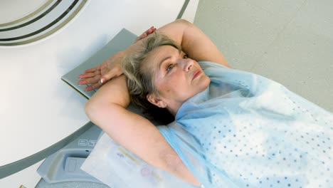 close-up shot of a female mature patient lying on a table of ct scan machine. computer tomograph scanning body and brain of elderly woman. high-tech equipment in medical clinic. 4k