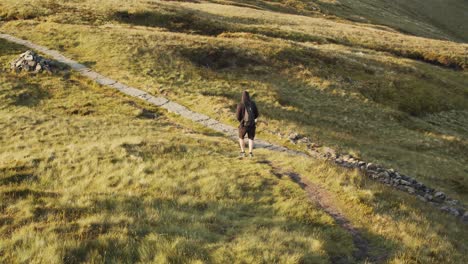 hiker walking down the slope of the kinder scout moorland plateau, peak district, derbyshire