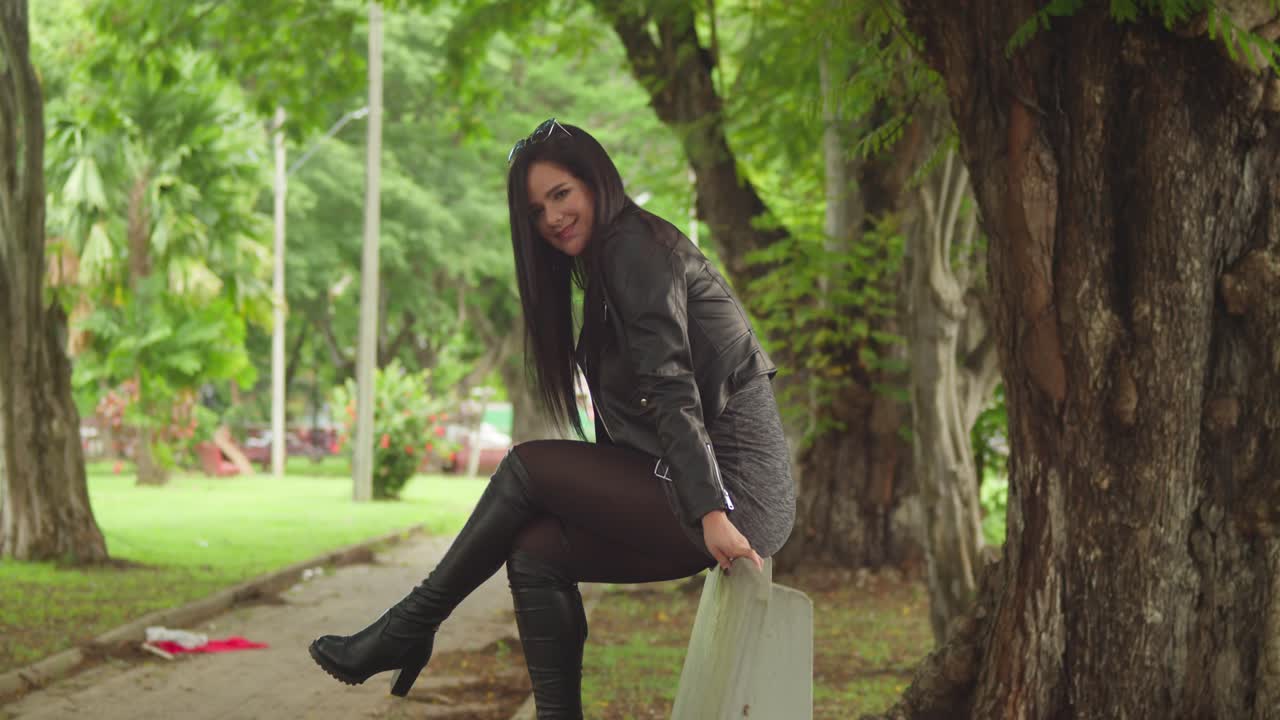 женщина в сапогах и куртке наслаждается днем в карибском парке, наполненном тропической красотой.