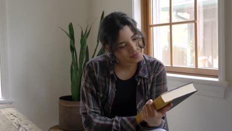 alegre chica puertorriqueña sonriendo disfrutando de terminar una historia de libro mirando la portada con aprecio