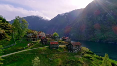 Flying-over-a-cliffside-village-in-Flam,-Norway-to-reveal-a-cruise-ship-in-the-fjord