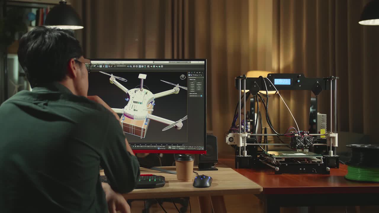 Back View Of Asian Engineer Thinking While Work On Personal Computer And 3D Printer, Screen Shows Cad Software With 3D Prototype Of Drone Delivery