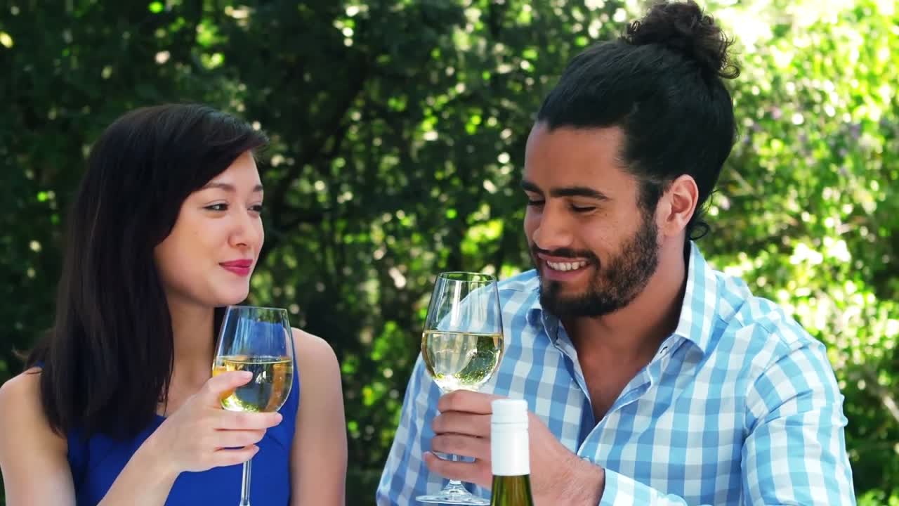 una pareja romántica sonriente brindando copas de vino