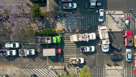 Static-overhead-view-of-a-pilgrimage-accompanied-by-garbage-trucks,-traffic-cut-through-on-a-sunny,-working-day,-Mexico-City