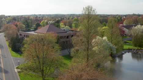 Toma-Aérea-Del-Edificio-De-Oficinas-De-Negocios-Entre-árboles-Florecientes-En-Un-Parque-Suburbano-En-Estados-Unidos,-Ee.uu.