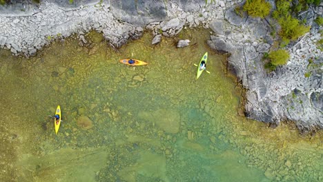 aerial overhead of color weekend kayakers enjoying the outdoors paddling through clear northern waters