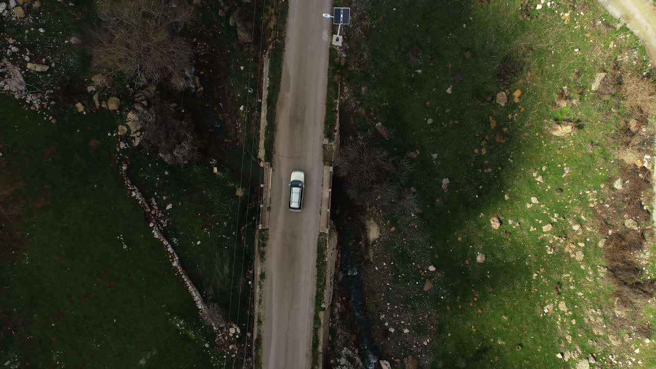 High aerial descending view above remote country road and white car, Lebanon