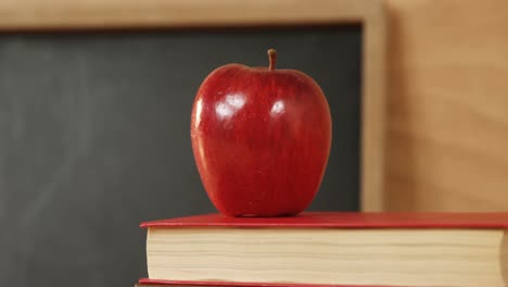 primer plano de libros apilados con manzana roja