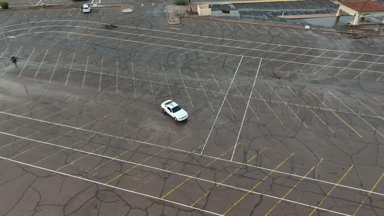 Aerial View of white Sports car doing donuts in empty parking lot, Car drifting on asphalt, Mesa Arizona