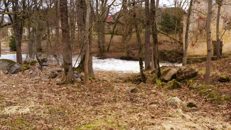 Drone-Dolly-A-Través-De-Un-Bosque-Vacío-Mientras-El-Agua-Sale-De-Una-Alcantarilla-Abandonada-Hacia-El-Río