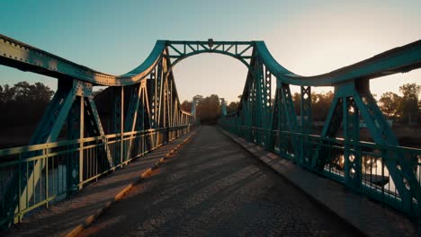 walking on a green, metal bridge at sunrise in poland