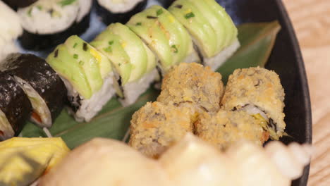 mixed serving of fresh sushi drizzled with oyster sauce in a platter - closeup shot slow motion