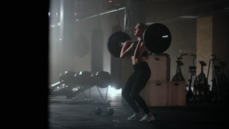 slow motion: a woman lifts a barbell in a dark gym with a lot of weight. a strong young woman lifts weights for a workout