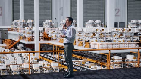 side view of full body asian business man talking on mobile phone in the warehouse